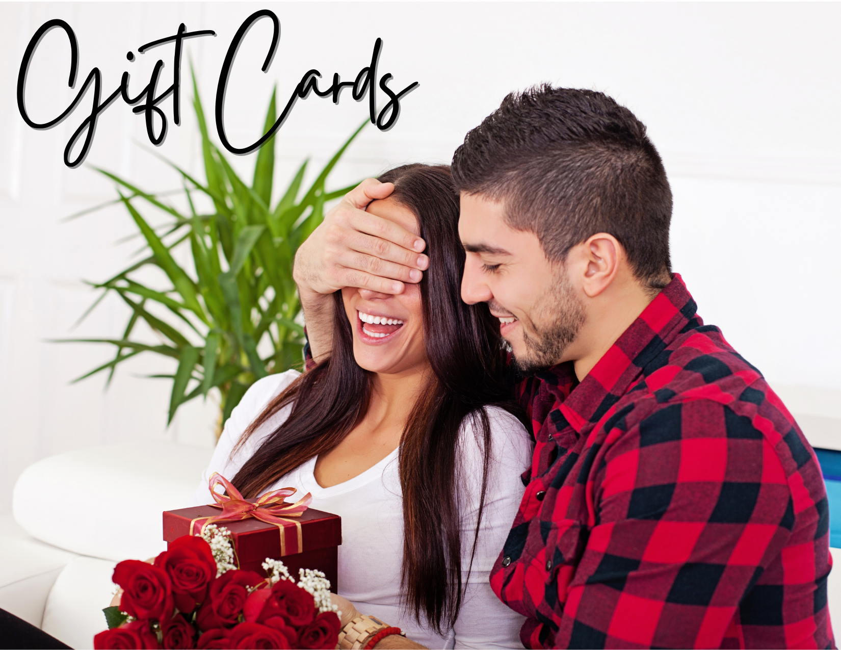 young good looking caucasian couple with the woman holding roses and a valentines gift and the man behind her with his hand over her eyes to surprise her